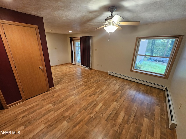 empty room with light hardwood / wood-style floors, baseboard heating, and ceiling fan