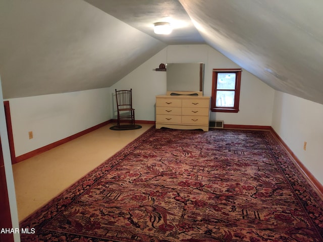 additional living space featuring dark colored carpet and lofted ceiling