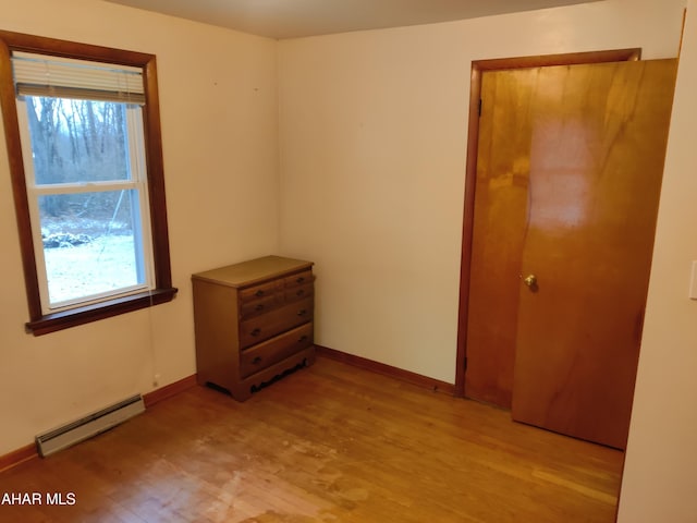 unfurnished bedroom with a closet, light hardwood / wood-style flooring, and a baseboard radiator