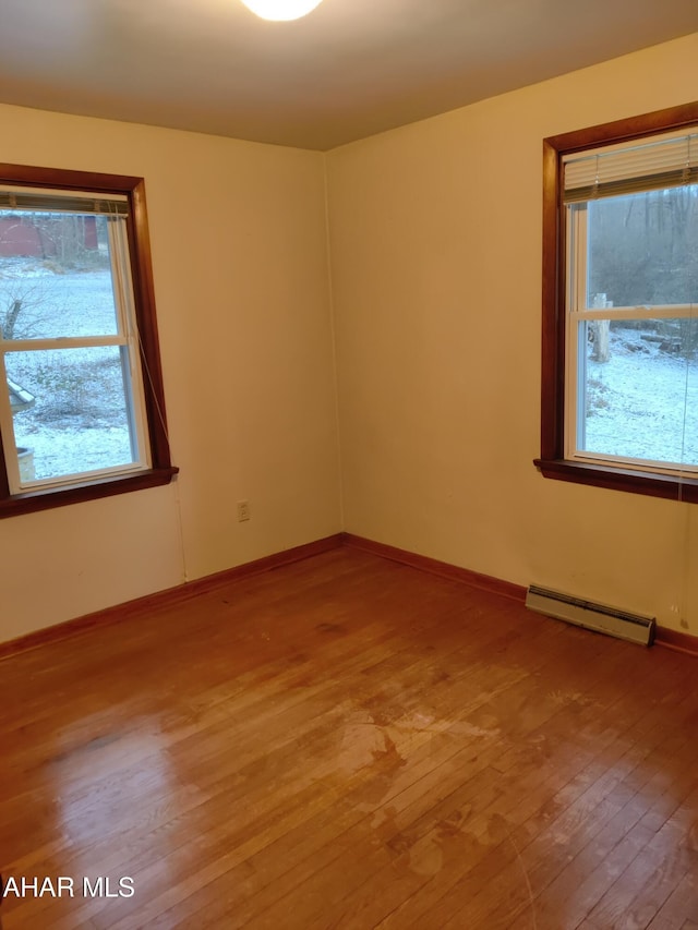 unfurnished room with light wood-type flooring, plenty of natural light, and baseboard heating