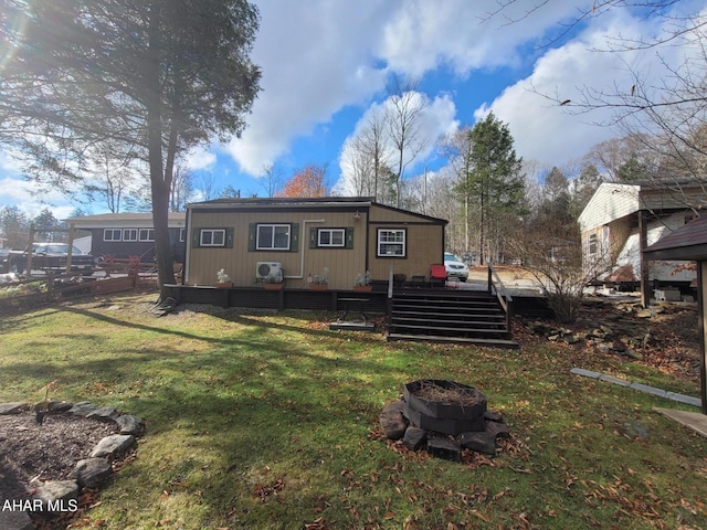 back of property with a yard and an outdoor fire pit