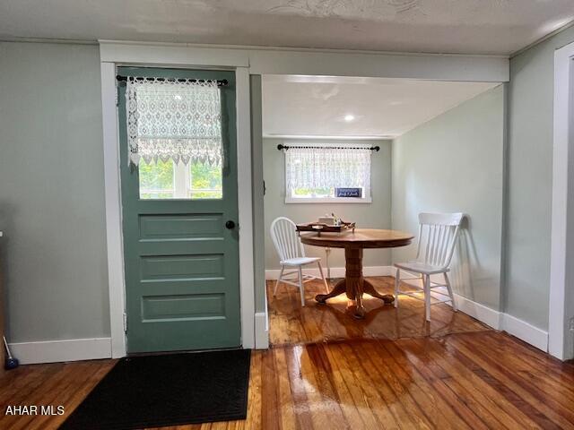 doorway featuring wood-type flooring and baseboards