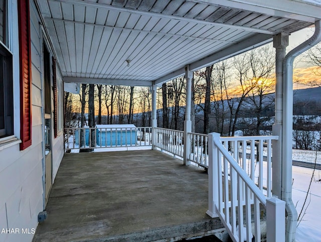 snow covered patio with a porch and a swimming pool