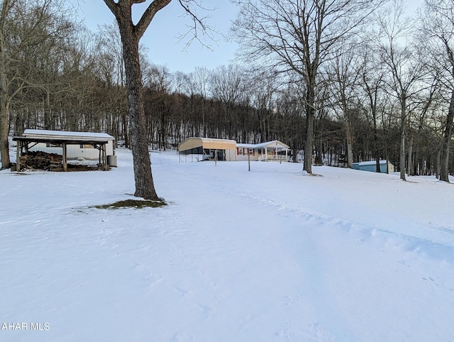 yard layered in snow featuring a carport