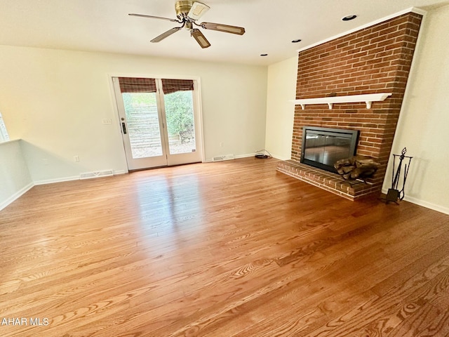 unfurnished living room with a brick fireplace, ceiling fan, and light hardwood / wood-style flooring