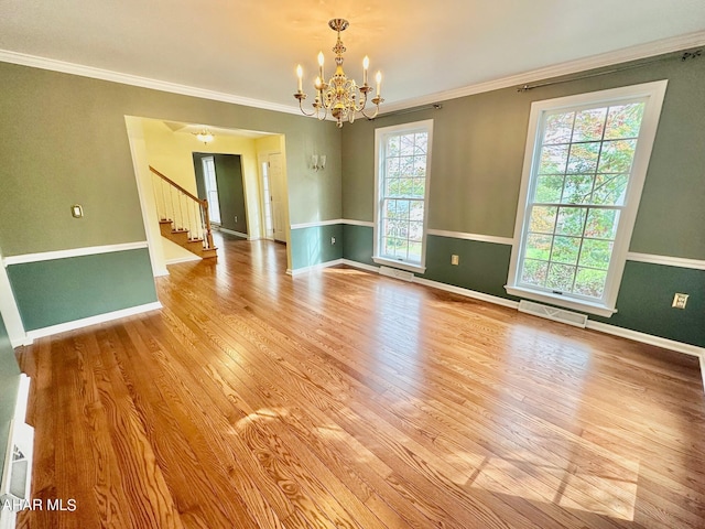 empty room with a chandelier, light hardwood / wood-style floors, and ornamental molding