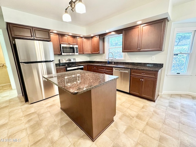 kitchen with dark stone countertops, a center island, sink, and stainless steel appliances