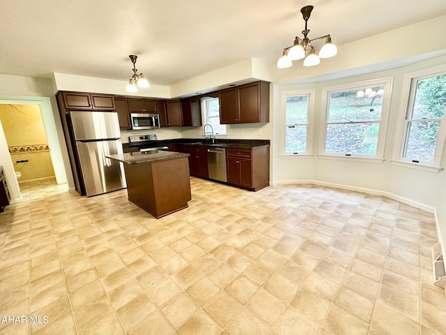 kitchen with sink, a center island, stainless steel appliances, a notable chandelier, and decorative light fixtures