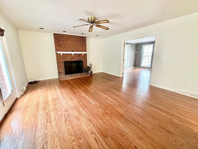 unfurnished living room with ceiling fan, light hardwood / wood-style floors, and a brick fireplace