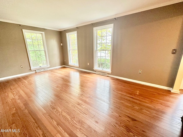 empty room with crown molding and light hardwood / wood-style floors