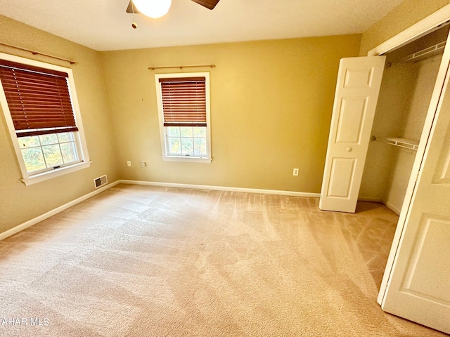 unfurnished bedroom with a closet, light colored carpet, multiple windows, and ceiling fan