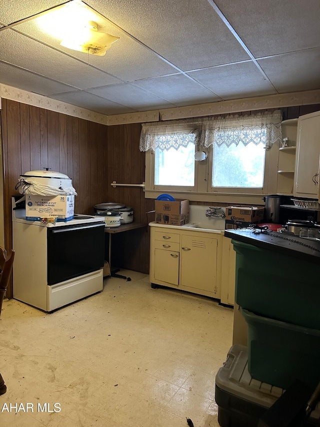 kitchen featuring stove, a paneled ceiling, a wealth of natural light, and wooden walls