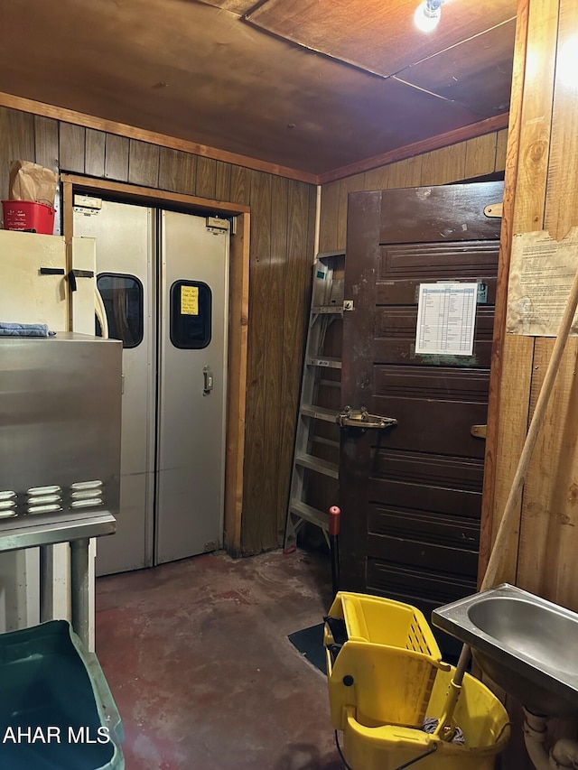 basement with stainless steel refrigerator with ice dispenser and wood walls