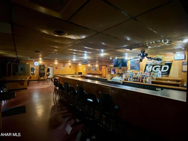 bar with a paneled ceiling and wood walls