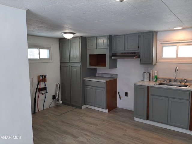 kitchen featuring gray cabinets, sink, a textured ceiling, and light hardwood / wood-style flooring