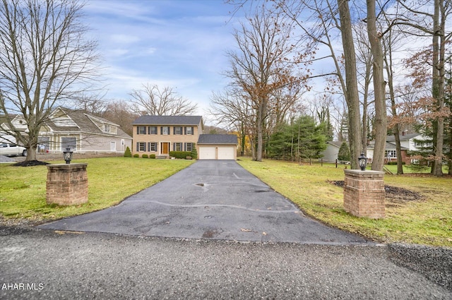 view of front of home featuring a garage, an outbuilding, and a front yard