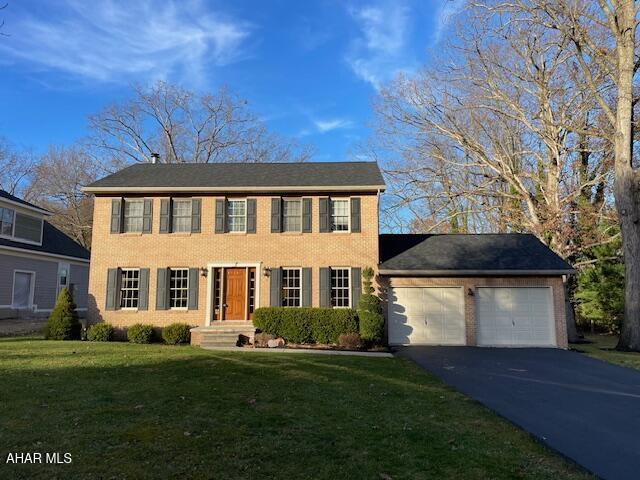 colonial inspired home with a front lawn and a garage