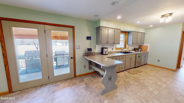 kitchen with light countertops, baseboards, gray cabinets, and a sink