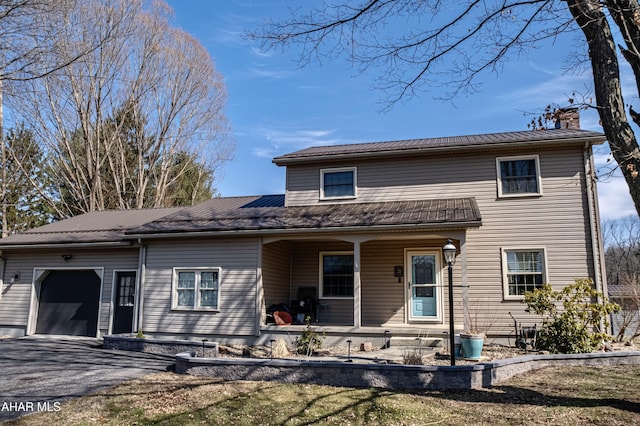 view of front of home featuring a porch, a chimney, driveway, and an attached garage