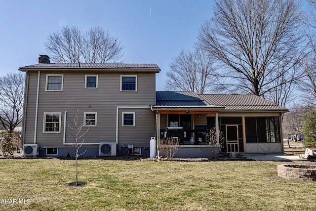 rear view of property featuring a chimney, a lawn, metal roof, and a sunroom