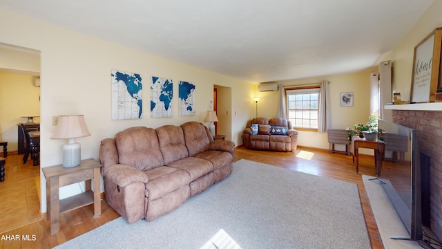 living area featuring wood finished floors, a wall unit AC, a fireplace, and baseboards