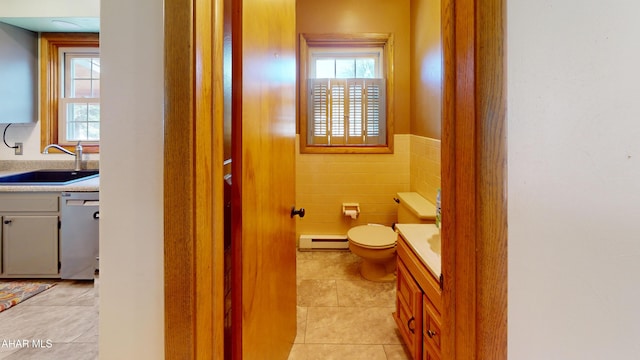 bathroom with a baseboard heating unit, toilet, tile walls, and vanity