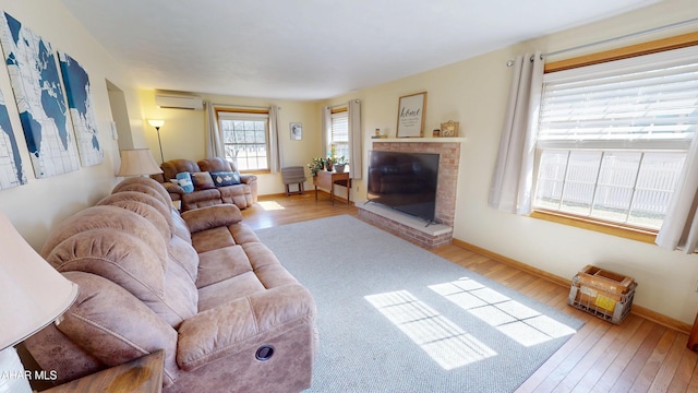 living area with baseboards, an AC wall unit, wood finished floors, and a fireplace