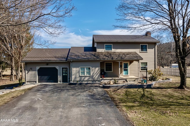 traditional-style home featuring driveway, metal roof, a front yard, a garage, and a chimney