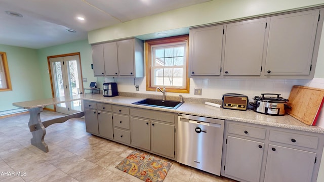 kitchen with stainless steel dishwasher, light countertops, plenty of natural light, and a sink