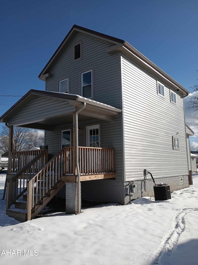 snow covered house featuring a porch