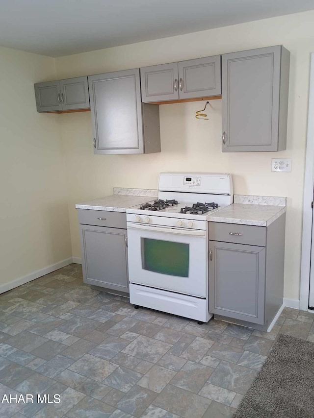 kitchen with white gas stove and gray cabinetry