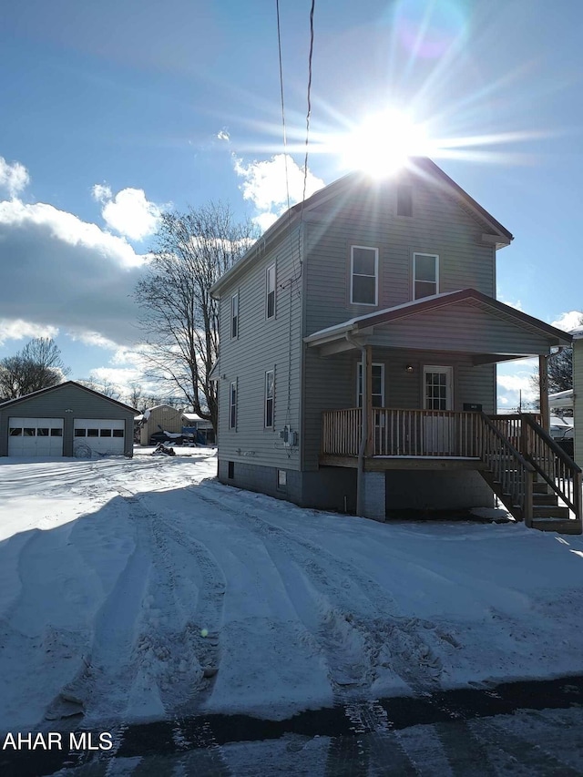 view of front of property featuring covered porch, a garage, and an outdoor structure