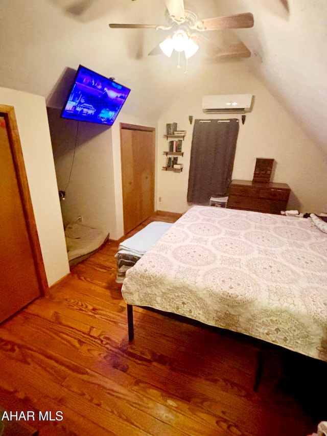 bedroom with lofted ceiling, wood finished floors, a ceiling fan, and a wall unit AC