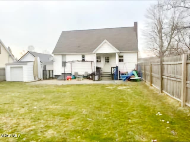 rear view of house featuring a fenced backyard, entry steps, an outdoor structure, and a yard