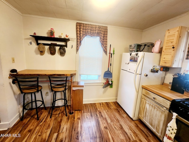 kitchen with range with gas cooktop, baseboards, ornamental molding, freestanding refrigerator, and wood finished floors