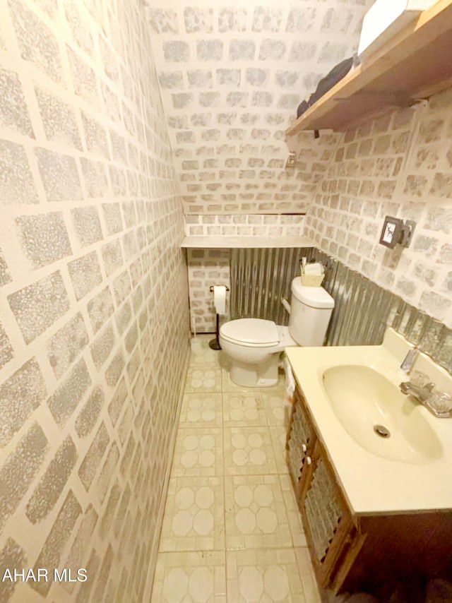 half bathroom featuring vanity, vaulted ceiling, toilet, and tile patterned flooring