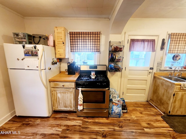 kitchen with ornamental molding, a sink, wood finished floors, freestanding refrigerator, and stainless steel gas range