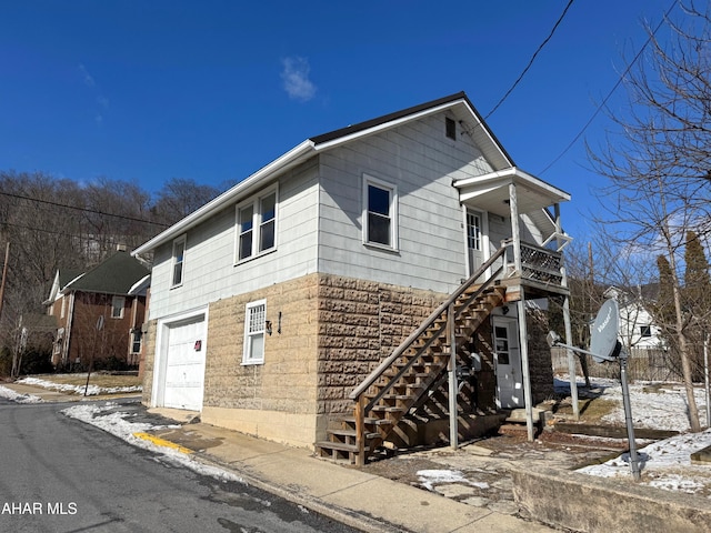 view of snowy exterior featuring stairway and an attached garage