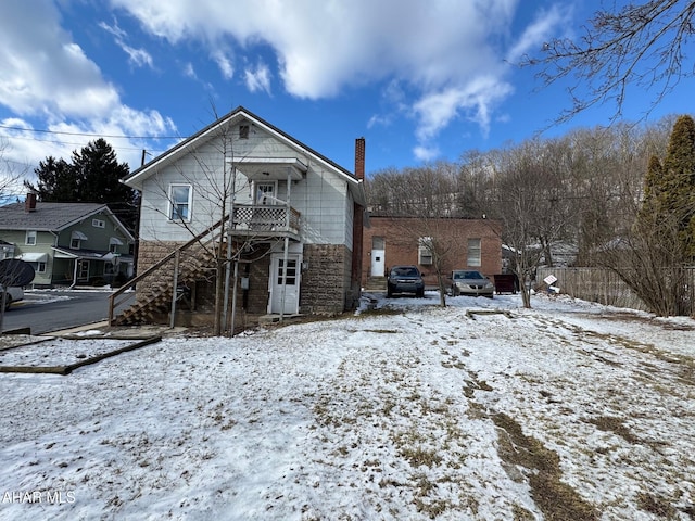 view of front of home with stairs, stone siding, and a chimney