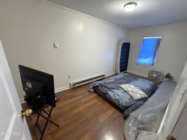 bedroom with a baseboard heating unit, crown molding, dark wood-style floors, and baseboards