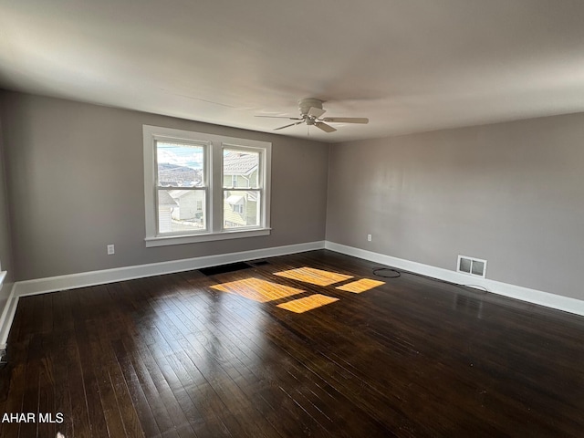 unfurnished room with dark wood-style floors, visible vents, baseboards, and a ceiling fan