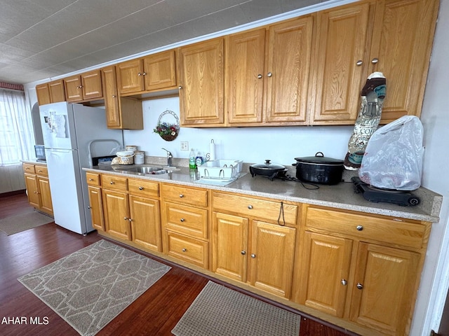 kitchen with dark wood-style flooring, brown cabinets, light countertops, freestanding refrigerator, and a sink