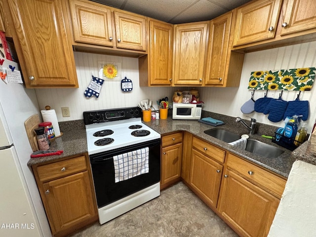 kitchen with white appliances, brown cabinets, a sink, and dark stone countertops