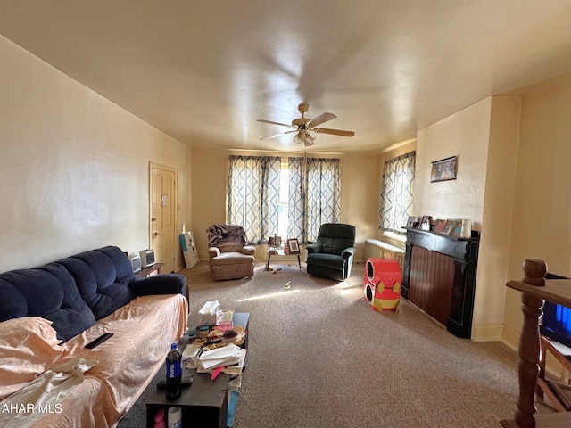 living area featuring carpet floors, ceiling fan, a fireplace, and baseboards