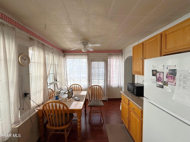 kitchen featuring brown cabinetry, black microwave, light countertops, and freestanding refrigerator