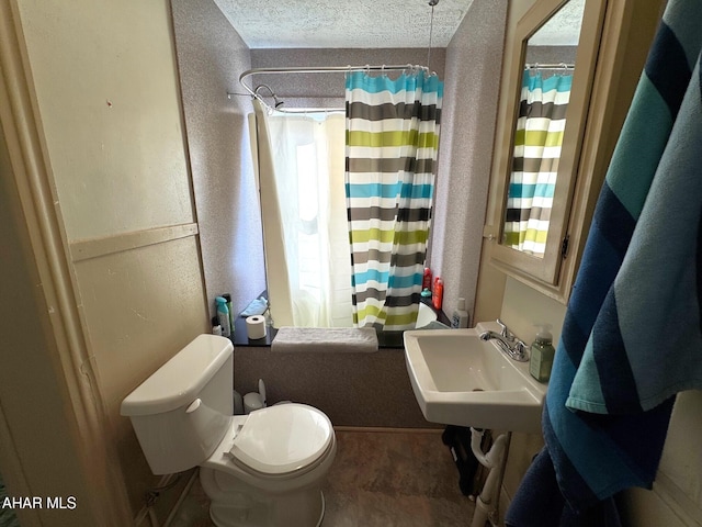 full bath featuring a textured wall, toilet, shower / bathtub combination with curtain, a textured ceiling, and a sink