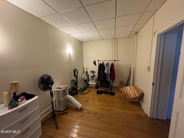 interior space with a drop ceiling, wood finished floors, and baseboards