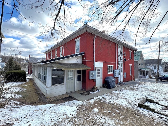 view of snow covered exterior with brick siding