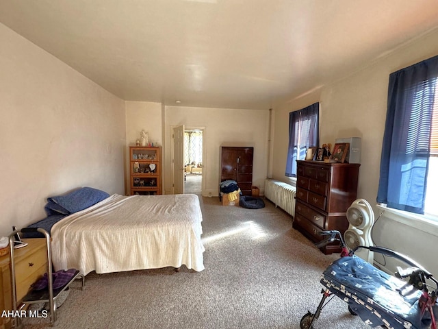 bedroom featuring multiple windows, radiator heating unit, and carpet flooring