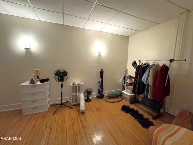 exercise area featuring a paneled ceiling, baseboards, and wood finished floors